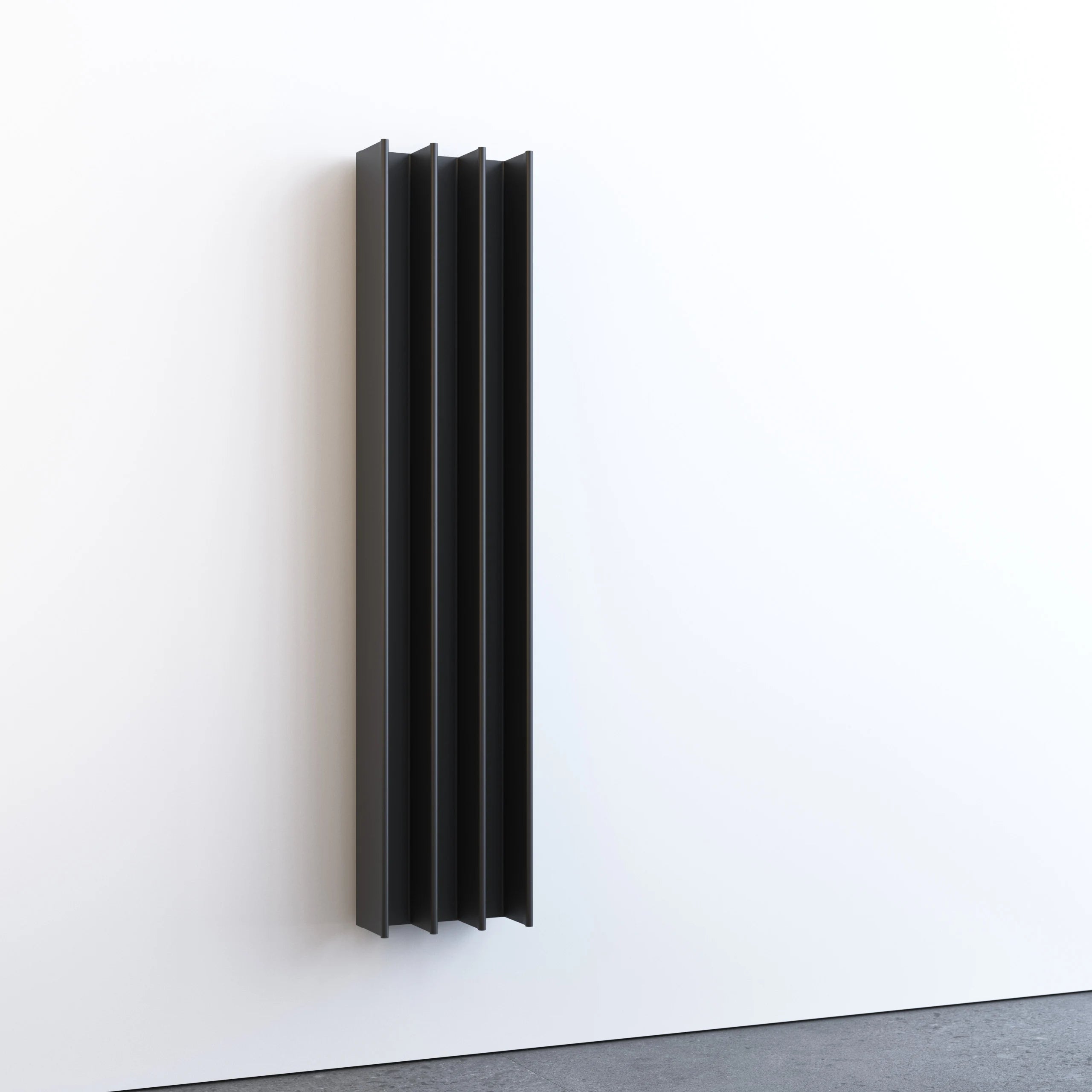 A space-saving vertical black heated towel rail mounted on a white wall.