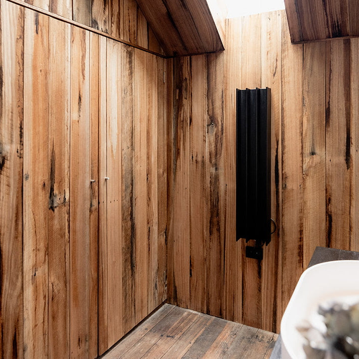Wooden interior with a modern design, featuring a ceiling light fixture and heated towel rail.