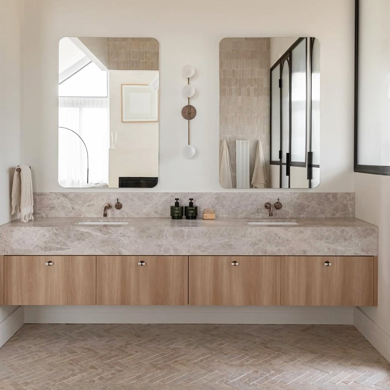 Bathroom vanity with double sink, mirrors, and decorative items.